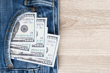Money In Pocket Of Blue Jean On Wooden Background With Copy Space.