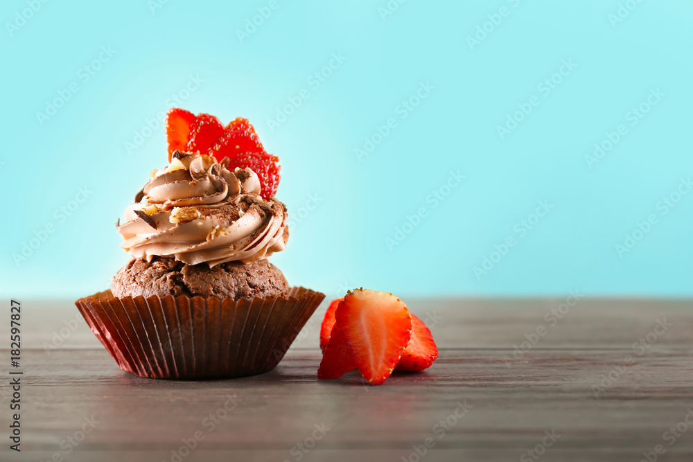 Tasty chocolate cupcake on table against color background