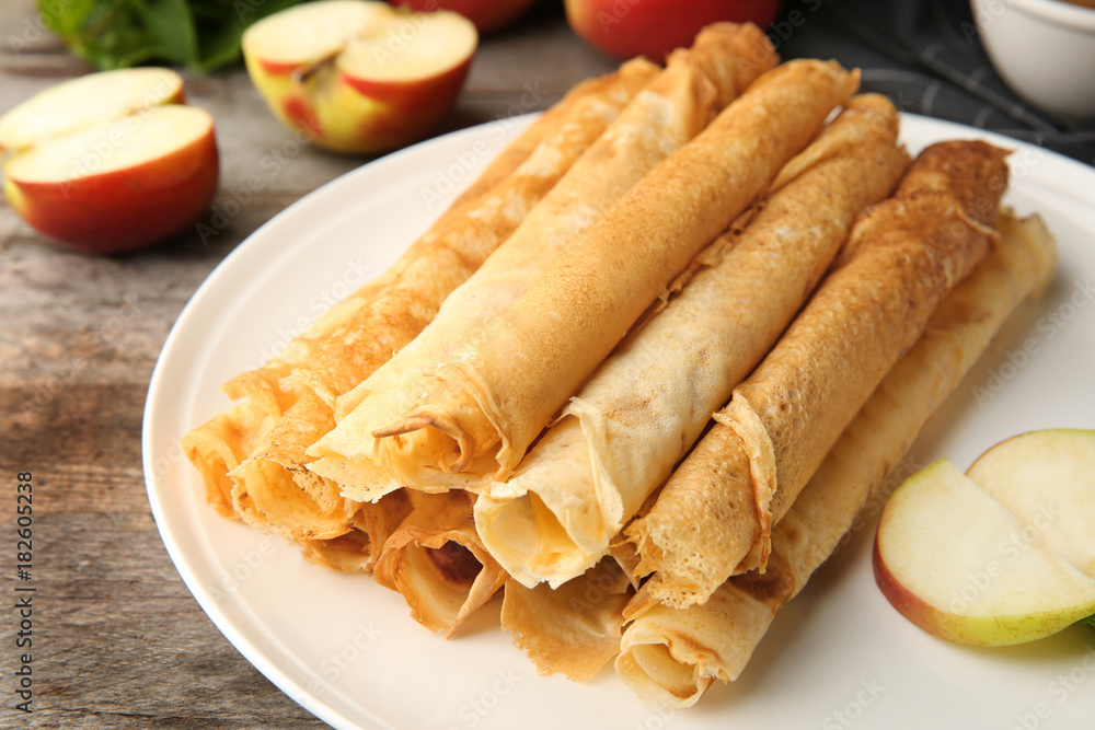 Plate with delicious thin pancakes on table