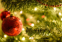 Beautiful Christmas Background - Red Baubles On A Background Of Blurred Lights On A Christmas Tree With Bokeh Effect.