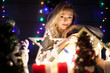 © DC Studio - Young woman with a gift box in her hands in christmas decorated room. Happiness and holiday spirit