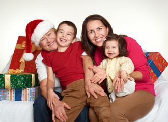 Wall Mural - Grandma, daughter and grandchild dressed in santa hat with gift boxes sit on sofa, white background. New year eve and christmas holiday concept.