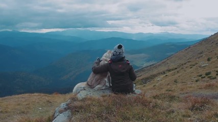 young caucasian female hiking in mountains with siberian husky dog