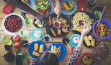 Fototapeta Uliczki - Top view of group of people having dinner together while sitting at wooden table. Food on the table. People eat fast food.