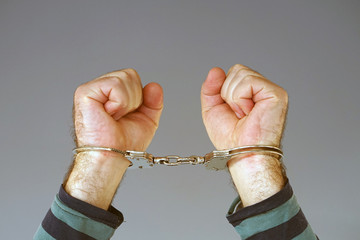 Close-up. Arrested man handcuffed hands at the back. Prisoner or arrested terrorist, close-up of hands in handcuffs