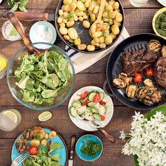 Wall Mural - Dinner table with grilled steak, vegetables, potatoes, salad, snacks, lemonade
