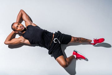 top view of young african american sportsman with closed eyes lying on grey