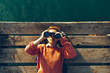 © tinyakov - Young Girl Lies On A Pier Near The Sea And Looks Through Binoculars. Travel Search Journey Concept