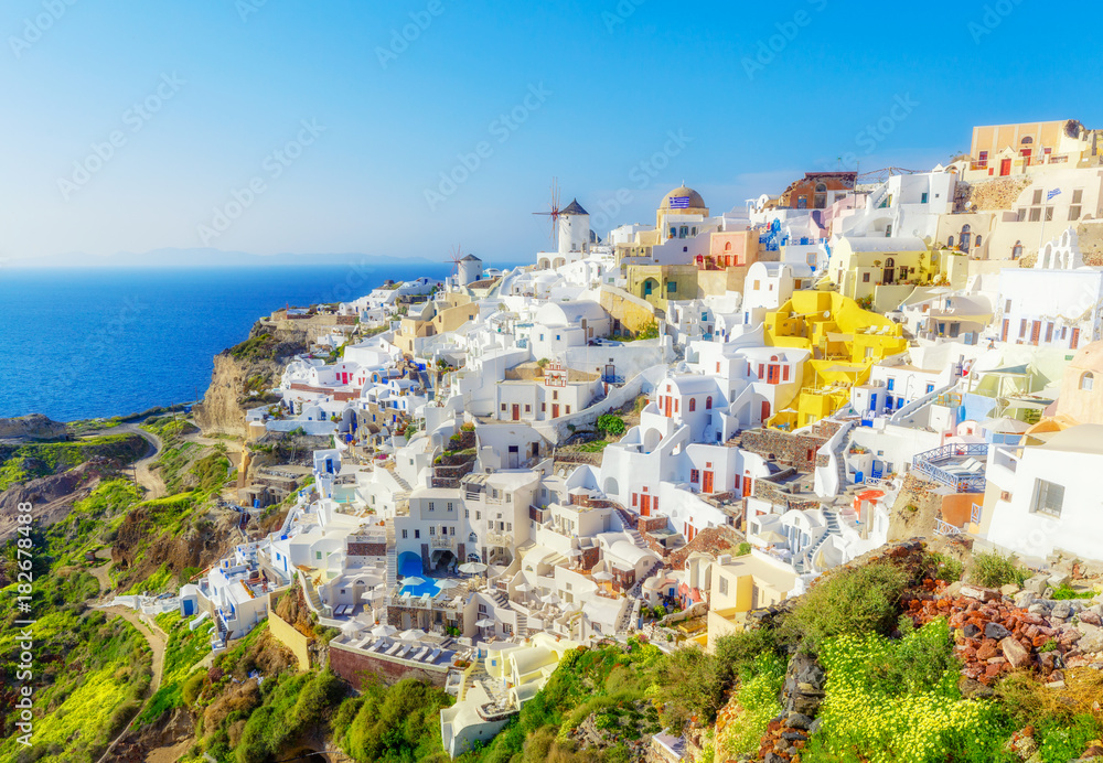 Greece, Santorini. Amazing view from famous sunset point on island in Aegean sea -  Santorini over Oia - Ia village at the slope of volcano. Famous windmills and traditional greek white architecture. - obrazy, fototapety, plakaty 