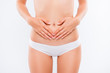 © deagreez - Concept of early term of pregnancy. Close up cropped photo of woman's abdomen and belly button, she is touching her slim stomach with two hands,girl wear panties, isolated on white background