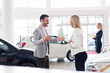 © NDABCREATIVITY - Professional salesperson selling cars at dealership to buyer