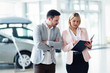 © NDABCREATIVITY - Professional salesperson selling cars at dealership to buyer