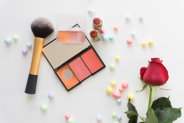 Top view make up with colorful balls and red rose on white background.