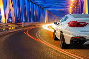 modern SUV driving across the bridge at night