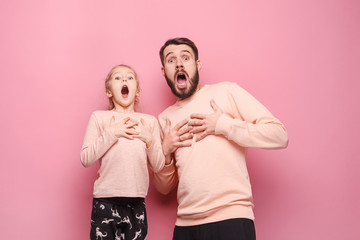 Surprised young family looking at camera on pink