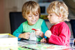 © Irina Schmidt - Two little blond kid boys playing together board game at home. Funny siblings having fun.