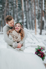 Wall Mural - Bride and groom are hugging in the winter forest. Couple in love. Winter wedding ceremony.