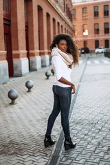 Wall Mural - Portrait of happy young hispanic woman with beautiful curly hair in the street.