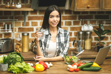 Portrait of a young woman drinking water in the kitchen at home