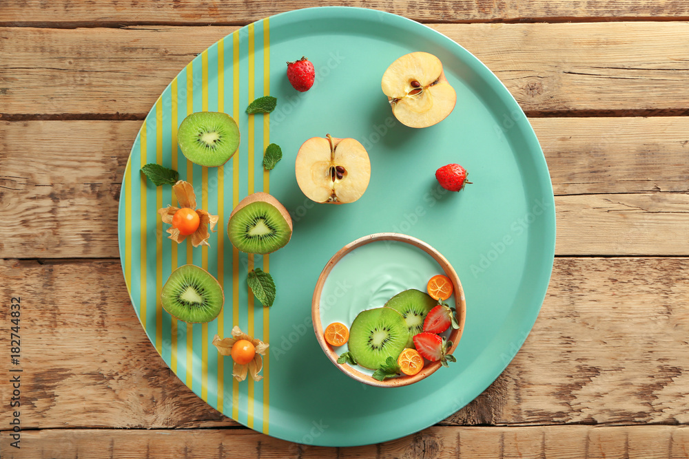 Bowl with yummy spirulina smoothie and bottle of drink on wooden table. Healthy vegan food concept