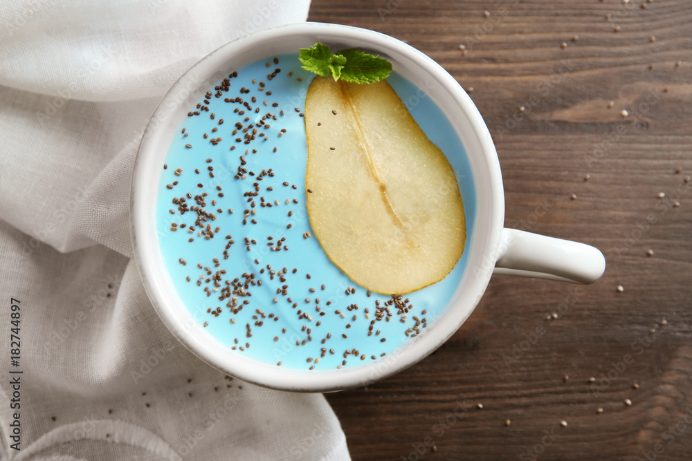 Bowl with yummy spirulina smoothie and bottle of drink on wooden table. Healthy vegan food concept