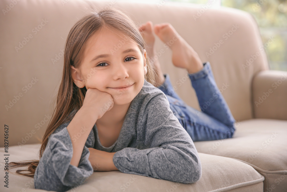 Cute little girl lying on sofa at home Stock Photo | Adobe Stock