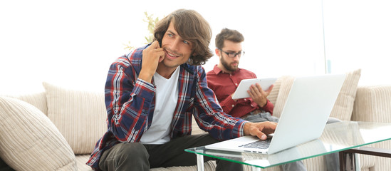 Canvas Print - two guys sitting on the couch, talking on the smartphone and communicating on the Internet.