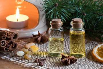 Two bottles of essential oil with cinnamon, star anise, frankincense and an aroma lamp