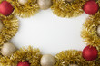 Golden and red Christmas balls and tinsel on white wooden background