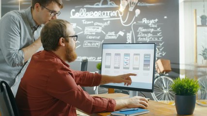Wall Mural - two male mobile game application developers talk while working on a personal computer, designing wir