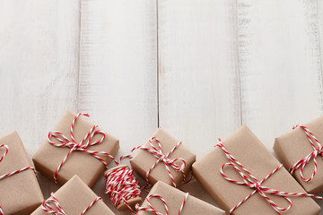 Wall Mural - Christmas gift or present boxes wrapped in kraft paper with striped baker's twine string on white wooden background, copy space