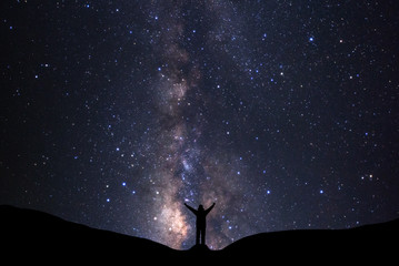 milky way galaxy with stars and silhouette of a standing happy man, long exposure photograph, with g