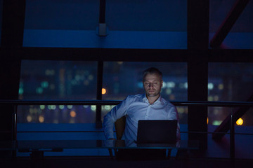 Businessman working on laptop in night office.