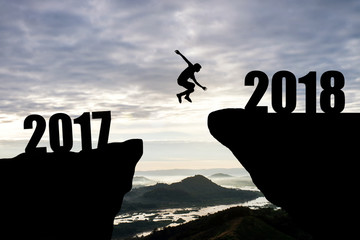 Man jump through the gap between hill.man jumping over cliff from 2017 to 2018 on sunset background,Business concept idea