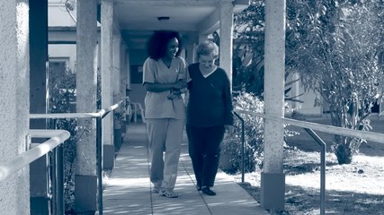 Poster - Nurse helping elderly woman in hospital garden. Sepia toned