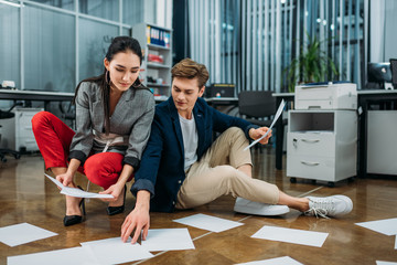 Wall Mural - young business partners doing paperwork while sitting on floor at office