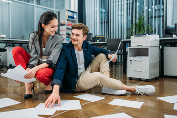 Wall Mural - young happy business partners doing paperwork while sitting on floor at office