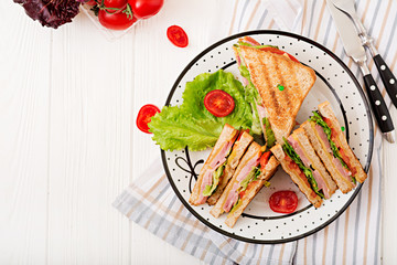 Club sandwich - panini with ham, cheese, tomato and herbs. Top view