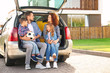 © Africa Studio - Young family with children sitting in car trunk near house
