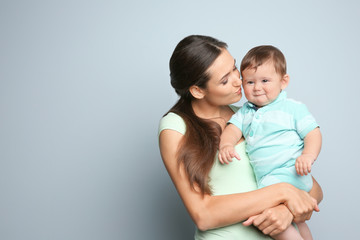 Canvas Print - Young mother with little son on color background