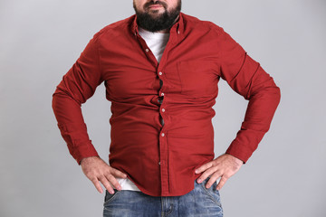 Poster - Overweight young man in tight red shirt on light background