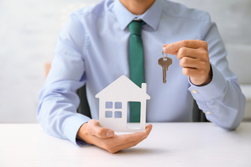 Poster - Real estate agent with key and house model at table