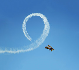 vintage biplane does loop stunt with smoke trails
