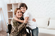 Woman veteran in wheelchair returned home. Son hugs mom in wheelchair.