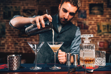 Wall Mural - close up Portrait of barman pouring fancy cocktail in bar at party. Manhattan cocktail beverage in nightclub