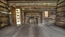 Pioneer Log Cabin Interior. Wooden Interior Of Historic Pioneer Cabin Living Room With Hardwood Floor And Fireplace.