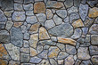 Large wall of natural granite stones of different size and color gray texture on a summer day