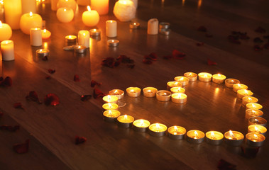 Wall Mural - Heart made of burning candles on floor in darkness