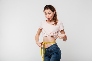 Wall Mural - Portrait of a slim pretty woman holding measuring tape