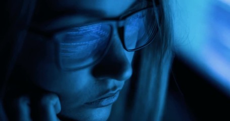 Computer screen and code reflected in woman's glasses